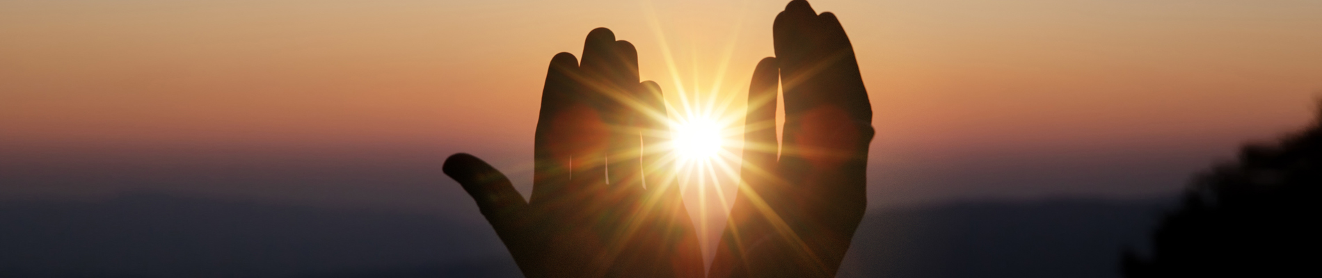 Two upright hands appearing to hold the setting sun