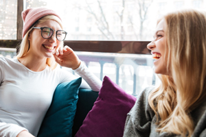 Two young ladies sitting on a couch laughing