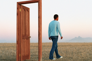 Man walking through a free-standing doorway on a grassy plateau