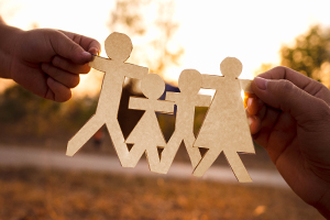 Hands holding a paper cutout of a family, father two kids and mom