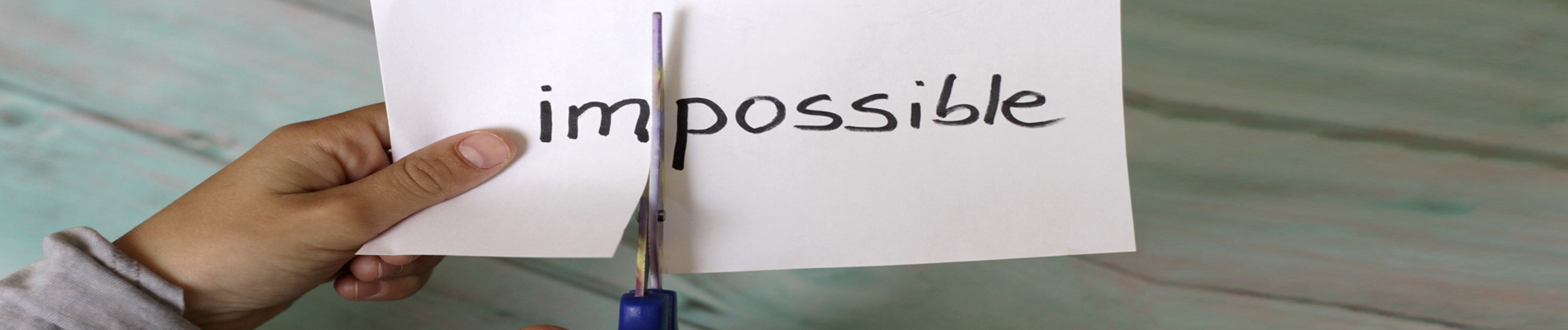 Paper being cut dividing the word impossible to possible
