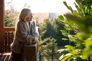 Woman leaning on a deck railing looking out over a valley