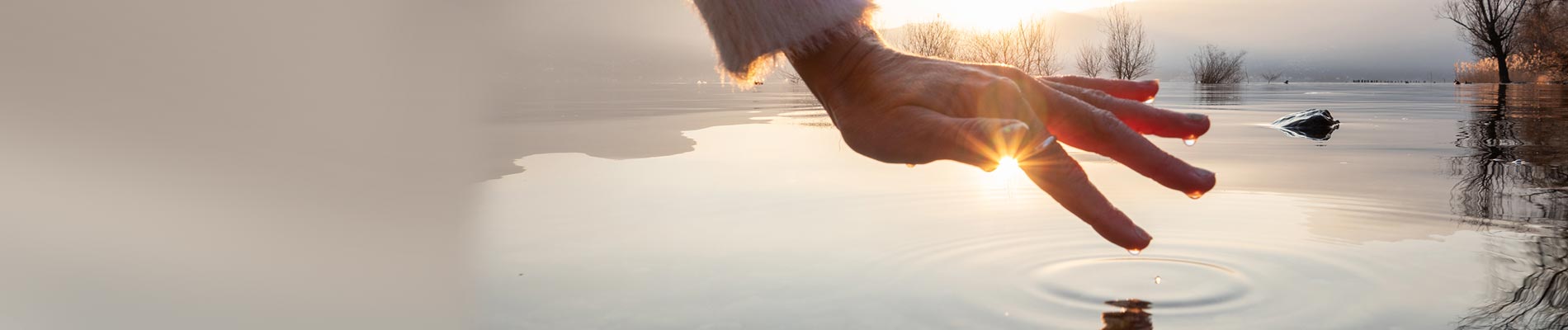 A woman's hand over water with drops fall making ripples