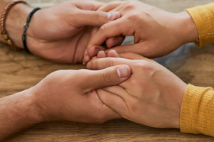 Two out stretched arms with holding hands