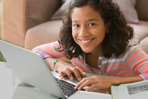 Young girl smiling and typing on a laptop