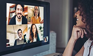Woman smiling on a video call with four other individuals
