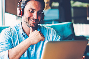 Man with headphones looking at his laptop with a smile on his face